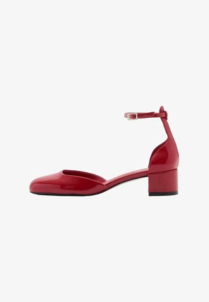 Zapato de tacón rojo de charol con correa en el tobillo, punta cuadrada, tacón bajo y superficie lisa. Diseño minimalista con cierre de hebilla ajustable.
