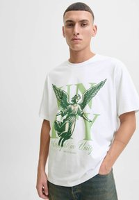 Bijela pamučna majica s zelenim grafičkim prikazom anđela, s velikim natpisom "JEDINSTVO" i "Izravno u jedinstvu" ispod slike.