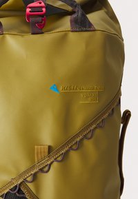 Olivgrüner Rucksack mit glatter Oberfläche, ausgestattet mit einem Reißverschluss mit bunten Akzentnähten, einem blauen Logo und einer kleinen Stoffschlaufe.