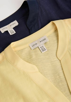 Două topuri Love & Roses pliate, unul bleumarin și unul galben pal, cu etichete de decolteu și mărime fabricate în Vietnam.