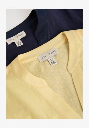 Două topuri Love & Roses pliate, unul bleumarin și unul galben pal, cu etichete de decolteu și mărime fabricate în Vietnam.