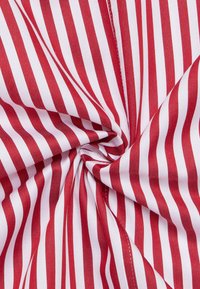 Tessuto a righe rosse e bianche, strettamente attorcigliato, con strisce verticali uniformemente distanziate. Il materiale sembra liscio con una leggera lucentezza.