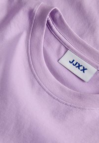 Λαμπερό μωβ βαμβακερό t-shirt με στρογγυλή λαιμόκοψη, λείες υφές και ετικέτα με το κείμενο "JJXX" σε μπλε χρώμα.