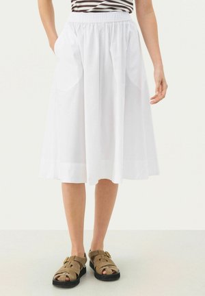 White, knee-length skirt with an elastic waistband, featuring side pockets and a smooth texture. Paired with brown, strappy sandals.