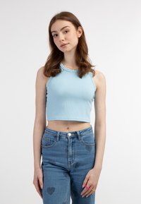 Top corto a coste azzurro chiaro con scollatura rotonda, abbinato a jeans in denim a vita alta con motivi a forma di cuore.
