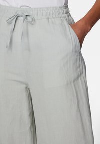 Lichtgrijze linnen broek met een elastische tailleband en een trekkoord, voorzien van zijzakken en een relaxte pasvorm voor comfortabel draagcomfort.