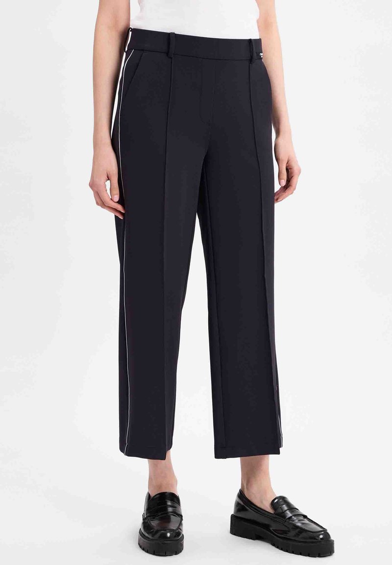 Marineblauwe wijde broek van lichtgewicht stof met verticale streepjes, voorzien van zijzakken en een gladde tailleband, gecombineerd met zwarte loafers.