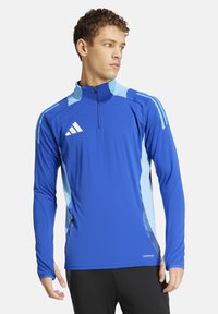 Blauwe sportieve longsleeve shirt met een kwart-rits kraag, contrasterende lichtblauwe accenten en textuurlijke zijpaneeldetails. Adidas-logo op de borst.