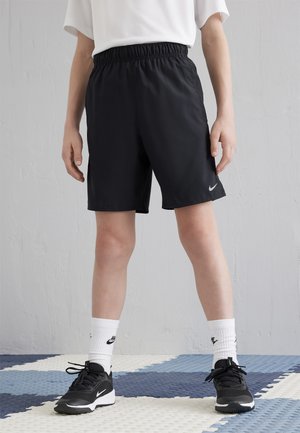 Melnas sporta šorti ar elastīgu jostu, īsas garuma un ar mazu baltu Nike logo. Pāris ar melnām kedām un baltām zeķēm.