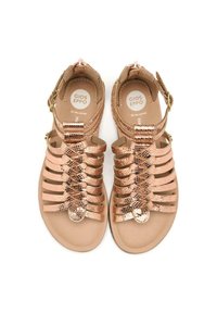 Sandalias de cuero color rosa dorado con múltiples correas estrechas, una plantilla lisa, hebilla ajustable en el tobillo y detalle de logo circular.