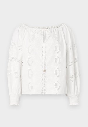 Camicia bianca con scollatura off-the-shoulder, maniche a sbuffo, dettagli in pizzo e parte anteriore arricciata. Completata con chiusura a fiocco e polsini arricciati.