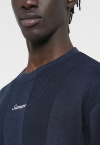 Sweatshirt tricoté texturé bleu marine avec un col arrondi et le logo "Samsøe" brodé sur la poitrine.