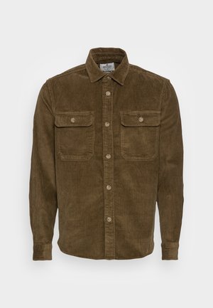 Brązowa koszula sztruksowa z długimi rękawami, kołnierzykiem, zapięciem na guziki z przodu i dwoma zapinanymi na guziki kieszeniami na piersi na jednolitym tle.