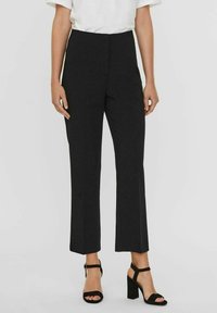 Pantalones negros de corte recto, con tejido suave, cintura alta y pliegue sutil en la parte delantera, combinados con sandalias de tacón negras.