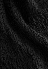 Black textured fabric featuring a wavy pattern, with a soft, slightly crinkled surface, creating depth and movement in the material.