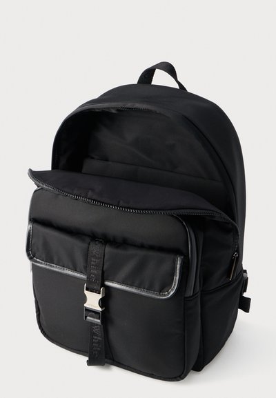 Μαύρο σακίδιο με ένα μεγάλο κύριο φερμουάρ και μια μπροστινή τσέπη κλειστή με μεταλλικό κούμπωμα και ρυθμιζόμενο λουρί.