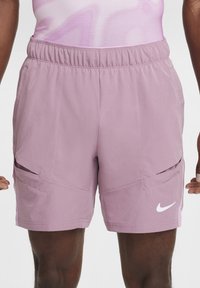 Nike shorts in lichtpaarse stof met een elastische tailleband, voorzien van twee voorkruiden en een witte logo-accent. Gladde textuur, sportief ontwerp.