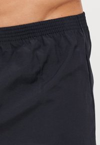Shorts légers bleu marine avec une taille élastique. Texture lisse et sans motifs ni accents visibles.