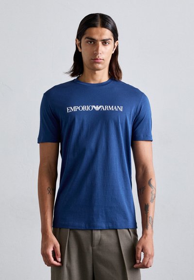 Navyblauwe katoenen t-shirt met een bedrukte "Emporio Armani"-logo over de borst, ronde hals en korte mouwen.