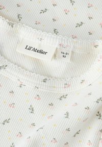 Weißes, geripptes Babyshirt mit kleinem Blumenmuster, gewelltem Ausschnitt und Lil’ Atelier Markenlabel, das Größe 1½-2 Jahre (92 cm) anzeigt.