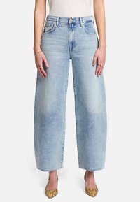 Jasnoniebieskie dżinsy szerokie w nogawkach, wykonane z denimu, z wysokim stanem, pięcioma kieszeniami i postrzępionymi dołami. Połączone z butami na obcasie w wężowy wzór.