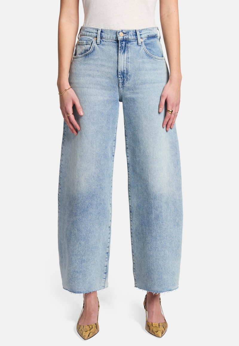 Jasnoniebieskie dżinsy szerokie w nogawkach, wykonane z denimu, z wysokim stanem, pięcioma kieszeniami i postrzępionymi dołami. Połączone z butami na obcasie w wężowy wzór.