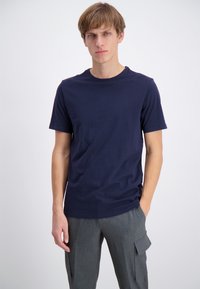 T-paita tummansinistä puuvillaa, jossa on pyöreä kaula-aukko ja lyhyet hihat, täydentävät harmaat cargo-housut, joissa on sivutaskut. Yksinkertainen malli ja istuvuus.