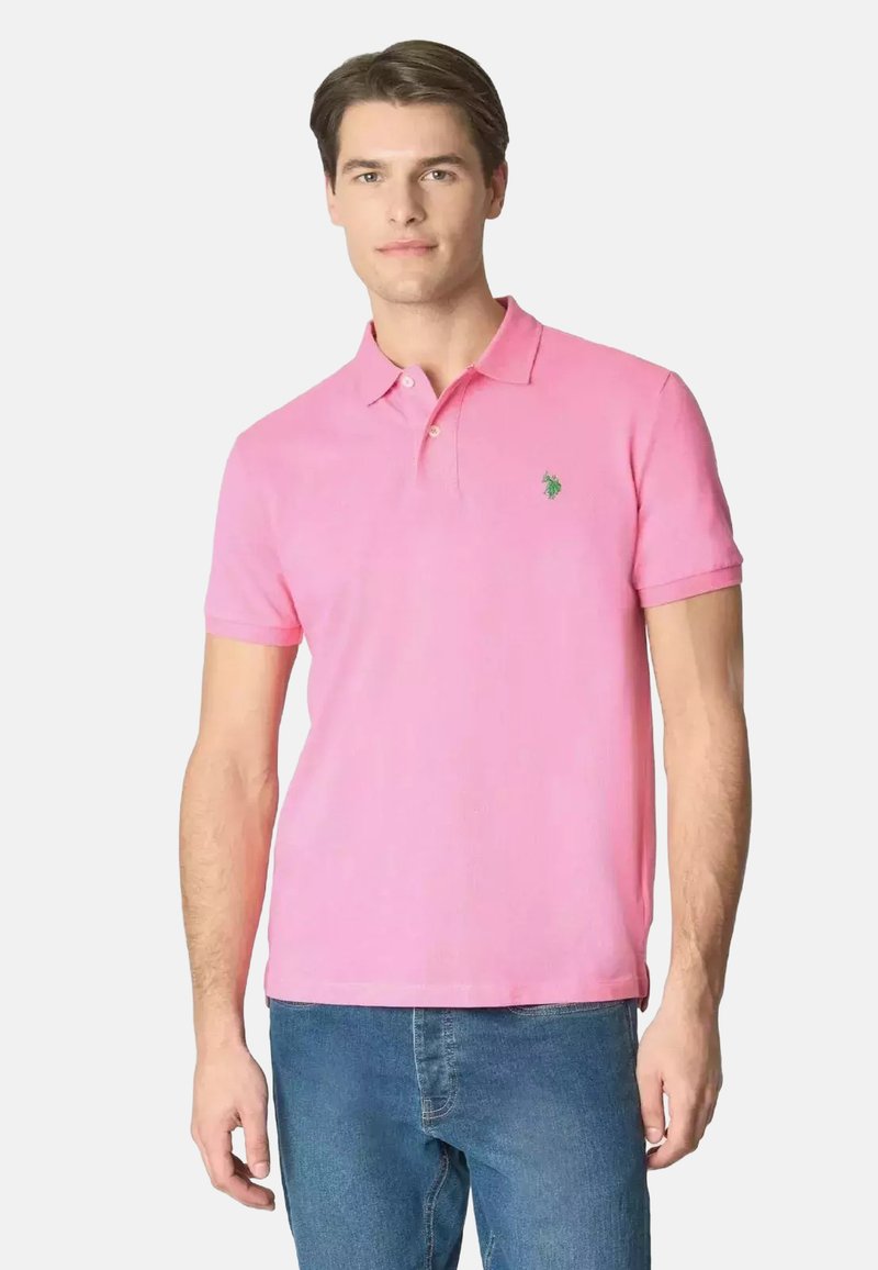 Polo a maniche corte in cotone rosa brillante, con colletto classico, tre bottoni e un piccolo logo verde sul petto.