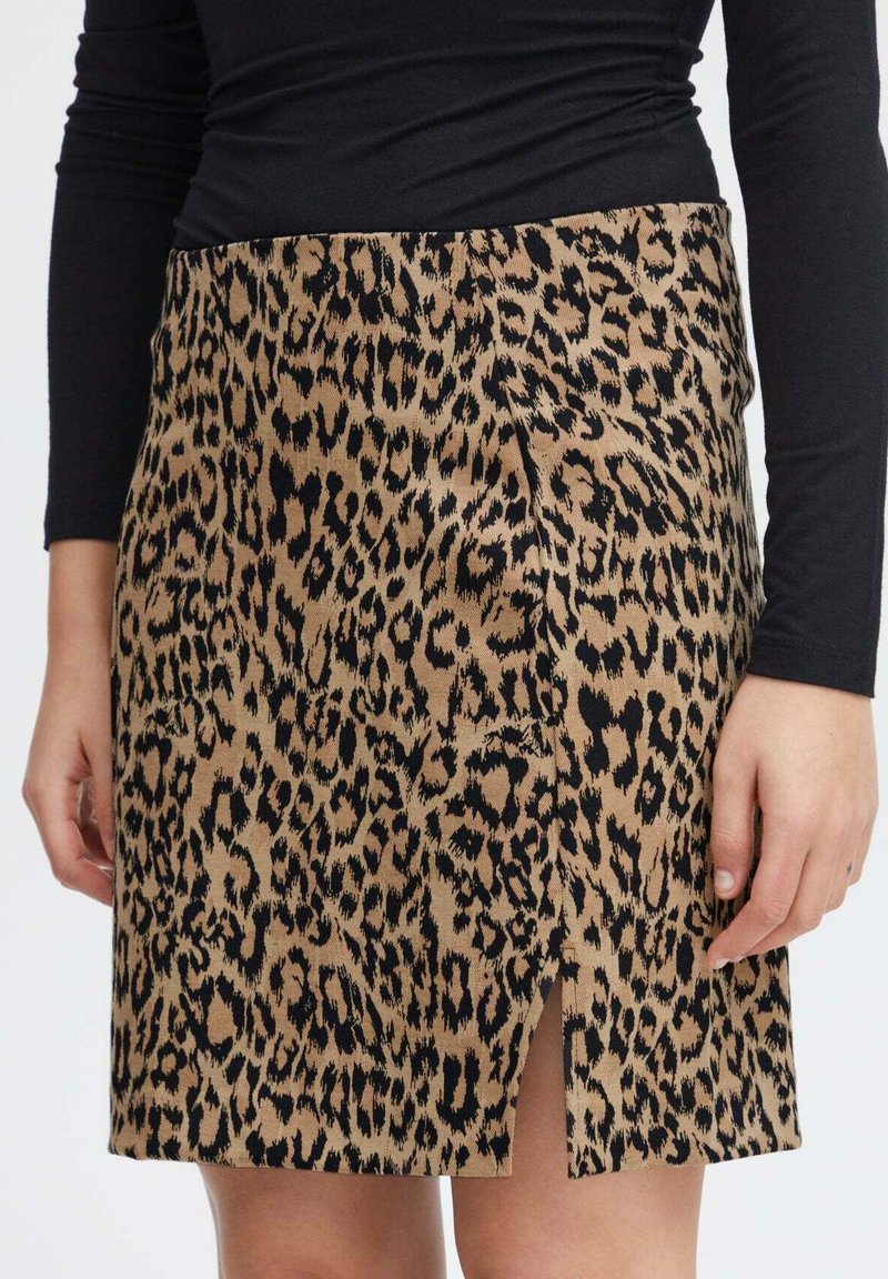Sukňa s leopardím vzorom v béžovej a čiernej farbe, s priliehavým strihom a bočným rozparkom. Vyrobená z mäkkej, textúrovanej látky.