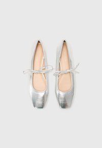 Metallic silver ballet flats with a square toe, smooth texture, and a decorative bow at the front. Inner lining is light beige.