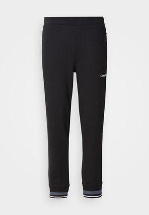 Zwarte sweatpants met een gladde textuur, een elastische tailleband en gestreepte boorden met blauwe en witte accenten. Logo op het linker been.