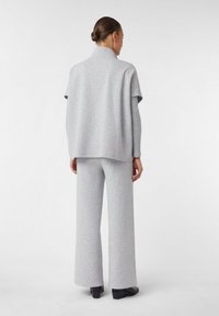 Top grigio a maglia con maniche corte, abbinato a pantaloni larghi grigi. Texture liscia, design minimale e dettaglio del colletto aderente.