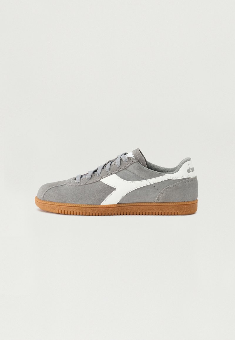 Grå semsket sneakers med hvite lærdetaljer, flate lisser og en brun gummisåle. Klassisk lavt design med en logo på hælen.