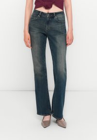 Mørk vaskede denim jeans med lige ben-design, med forlommer, bæltestropper og let lysning på lårene.