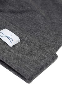 Gray knit fabric with a soft texture, featuring a visible white label with blue lettering at the edge. The design is folded and angled.