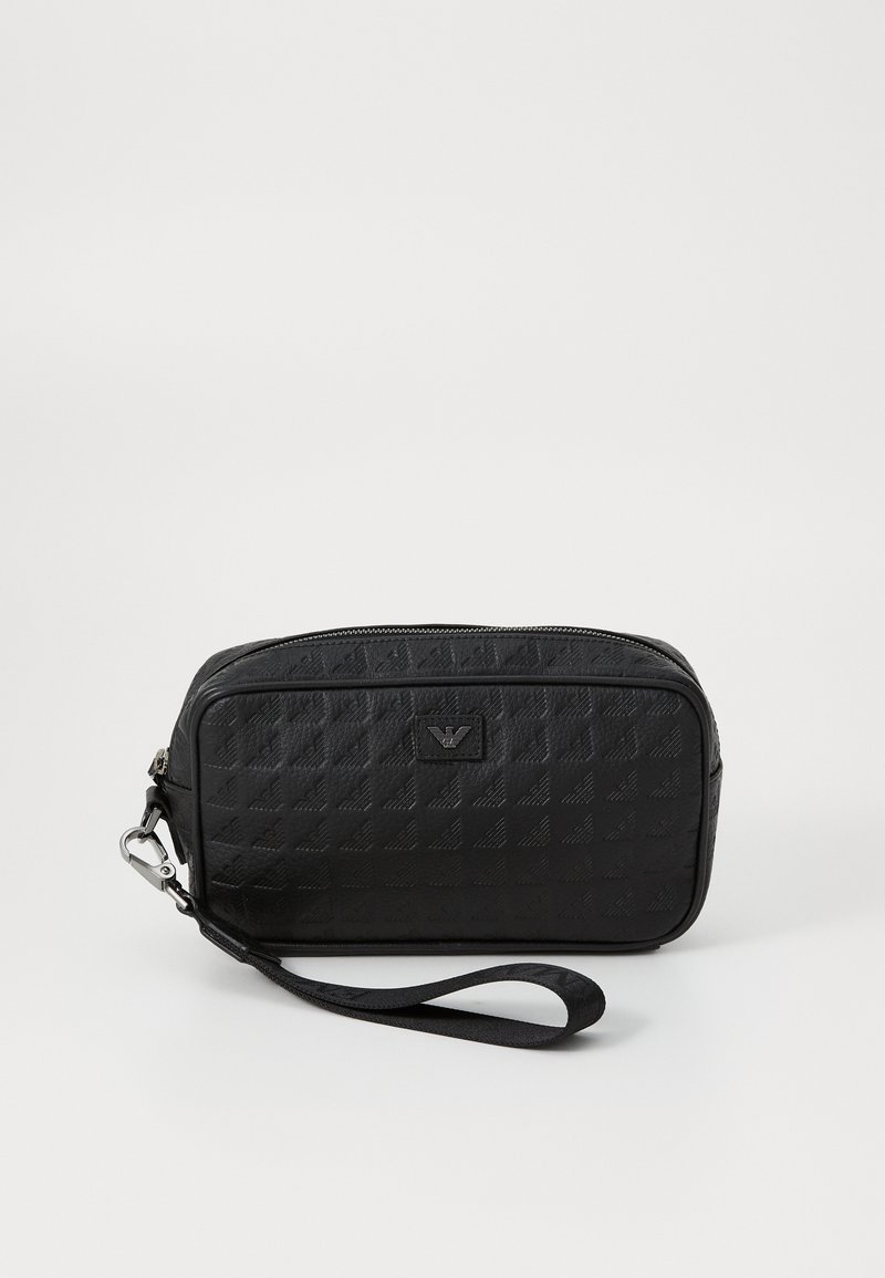 Črna teksturirana torbica z zadrgo, ki ima snemljiv trak in embosirani logotip spredaj. Kompaktna pravokotna zasnova.