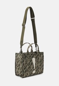 Bolsa de tote en verde oliva oscuro con un patrón geométrico repetido. Cuenta con dos asas superiores y una correa para el hombro ajustable. Acento notable: un gran signo de exclamación blanco.