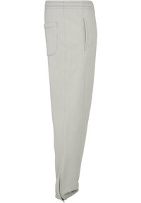 Hellgraue Sweatpants mit lockerer Passform, elastischem Bund, seitlichen Nahttaschen und Reißverschluss an den Knöcheln. Strukturierter Stoff.