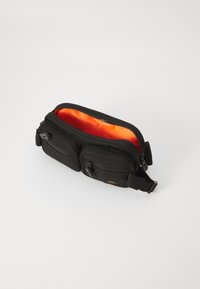 Μαύρη υφασμάτινη θήκη με πορτοκαλί εσωτερικό, διαθέτει διπλούς φερμουάρ και ρυθμιζόμενο λουράκι για ευελιξία. Υφή εξωτερικής επιφάνειας.