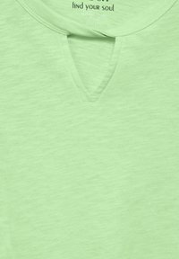 Ljusgrön t-shirt i mjukt material, med en subtil textur, en V-hals med en liten utskärning och en avslappnad passform.