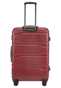 Valigia rigida rossa con superficie testurizzata, design a coste, manico retrattile e quattro ruote per la mobilità.