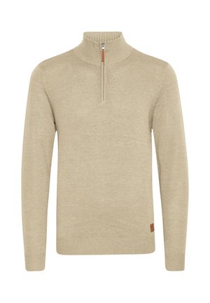Suéter de color beige hecho de una tela suave, con un cuello de media cremallera, puños y dobladillo acanalados, y una pequeña etiqueta de cuero marrón en el lateral.