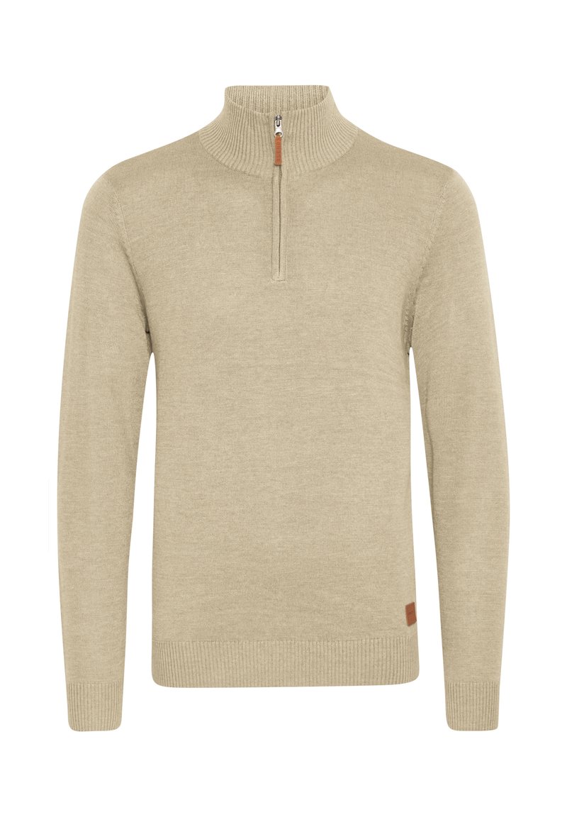 Suéter de color beige hecho de una tela suave, con un cuello de media cremallera, puños y dobladillo acanalados, y una pequeña etiqueta de cuero marrón en el lateral.
