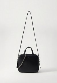 Μαύρη δερμάτινη τσάντα χειρός με τετράγωνο σχήμα, διπλές λαβές και αποσπώμενο ιμάντα αλυσίδας. Διαθέτει λείο υλικό και διακριτική λεπτομέρεια λογότυπου.