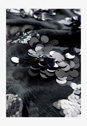 Mustast kangast, millel on tekstuurse pinnaga hallatav muster, on paigutatud läikivate mustade ja hõbedaste litrite ringikujulisi kujundeid, luues peegeldava mustri.