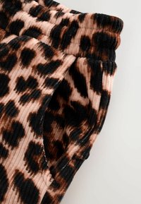 Tifă de leopard cu o textură moale, ribbată în nuanțe de negru, maro și roz deschis. Detaliu cu talie elastică.