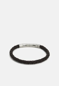 Braided black leather bracelet with a smooth, metallic clasp featuring engraved brand details. The design is circular and textured.