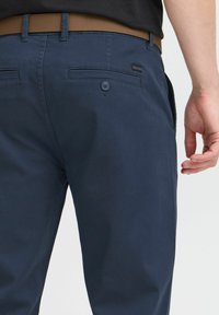 Pantalones de marino fabricados con una tela suave, que cuentan con un bolsillo trasero con botones, passantes para cinturón y un diseño ajustado.
