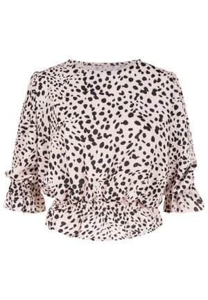 Blouse rose clair avec pois noirs irréguliers, taille cintrée, poignets à volants et manches bouffantes trois-quarts.