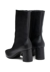 Botas negras de media caña con piel texturizada, tacones cuadrados redondeados y cremalleras en los laterales para el cierre, anguladas para mostrar el lado trasero y exterior.